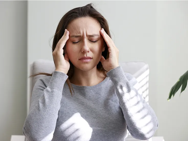 Mujer con expresión de dolor sujetándose la cabeza por una migraña.