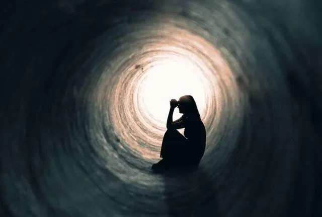 persona con sensación de vacío y tristeza persistente caminando al final de un túnel oscuro